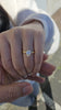Pear shaped diamond engagement ring with a polished 18kt yellow gold band by TJ Gold & Diamond, worn on a hand.