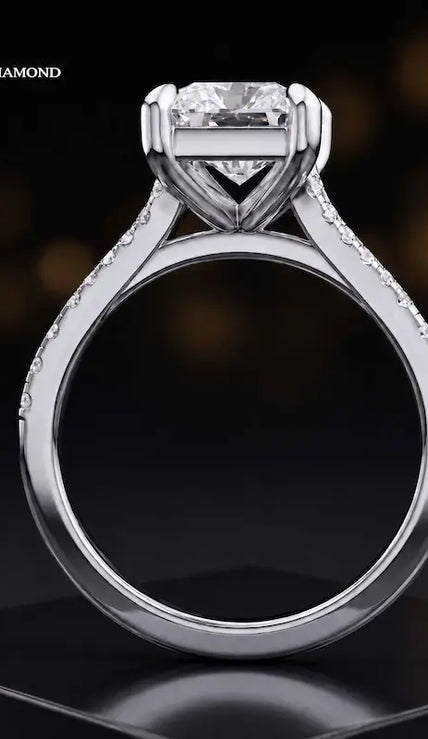 Side view of a radiant cut split shank lab-grown diamond engagement ring featuring a four-claw cathedral setting in 18kt white gold.