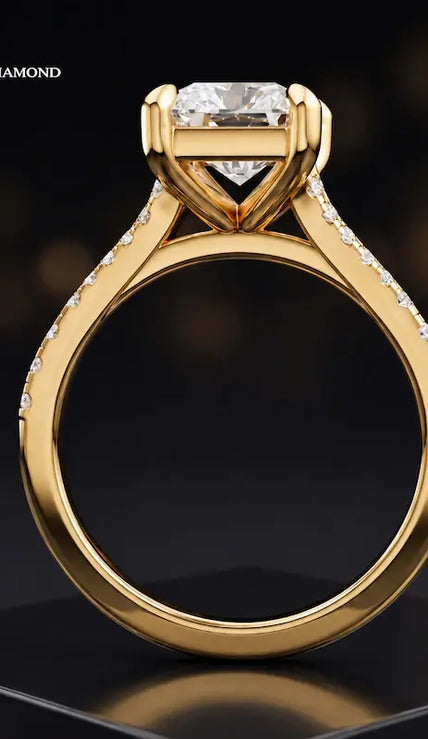 Side view of a radiant cut split shank lab-grown diamond engagement ring featuring a four-claw cathedral setting in 18kt yellow gold.