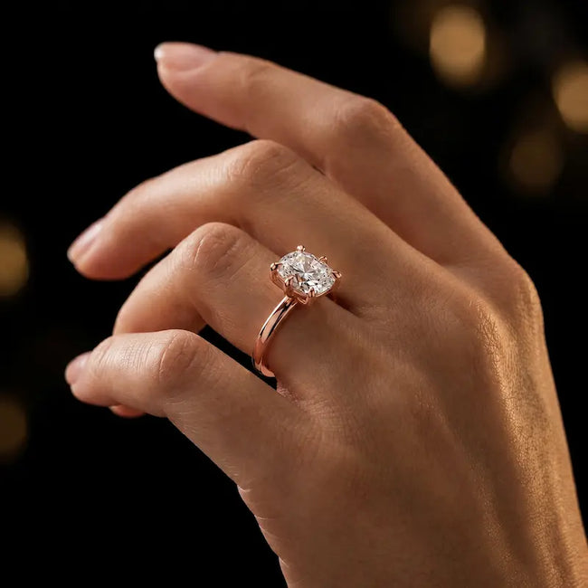 1.5 carat cushion cut diamond solitaire engagement ring in an 18kt rose gold 6 claw setting worn on a hand, by TJ Diamond