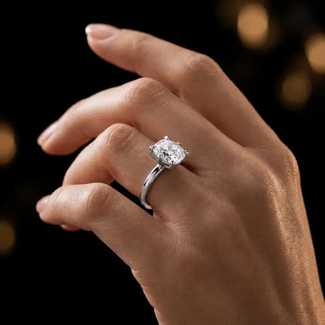 1.5 carat cushion cut diamond solitaire engagement ring in an 18kt white gold 6 claw setting worn on a hand, by TJ Diamond