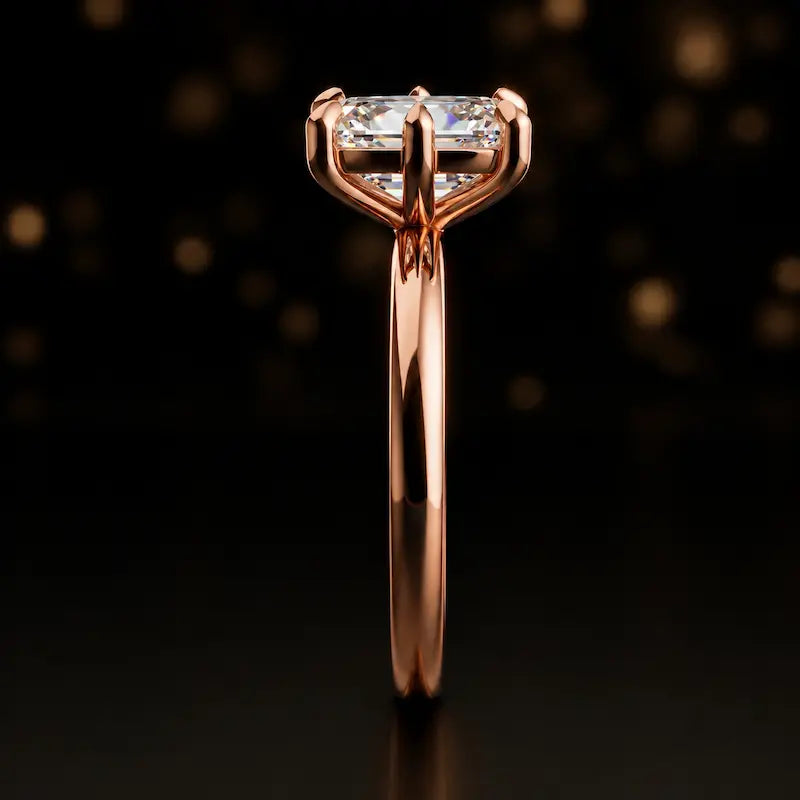 Side profile of a 1.5 carat emerald cut diamond solitaire engagement ring showing the cathedral setting and 18kt rose gold band by TJ Diamond