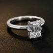 Angled view of a 1.5 carat emerald cut diamond solitaire engagement ring in an 18kt white gold 6 claw setting by TJ Diamond