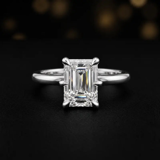 Front view of a 1.5 carat emerald cut diamond solitaire engagement ring in an 18kt white gold 6 claw setting by TJ Diamond