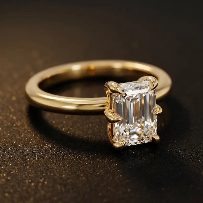 Angled view of a 1.5 carat emerald cut diamond solitaire engagement ring in an 18kt yellow gold 6 claw setting by TJ Diamond