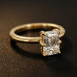 Angled view of a 1.5 carat emerald cut diamond solitaire engagement ring in an 18kt yellow gold 6 claw setting by TJ Diamond