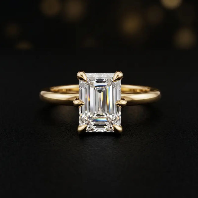 Front view of a 1.5 carat emerald cut diamond solitaire engagement ring in an 18kt yellow gold 6 claw setting by TJ Diamond