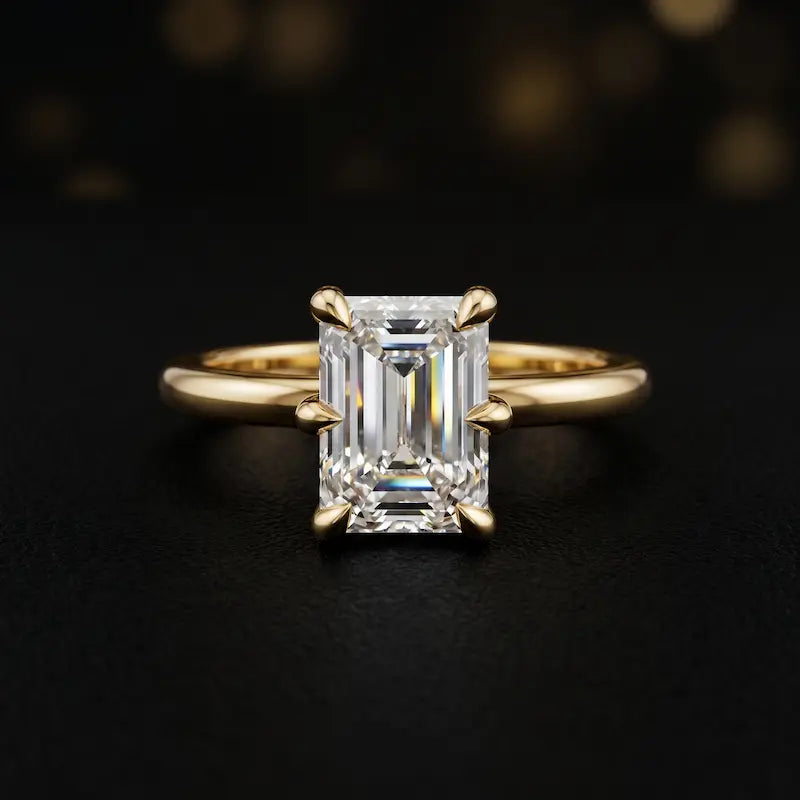 Front view of a 1.5 carat emerald cut diamond solitaire engagement ring in an 18kt yellow gold 6 claw setting by TJ Diamond