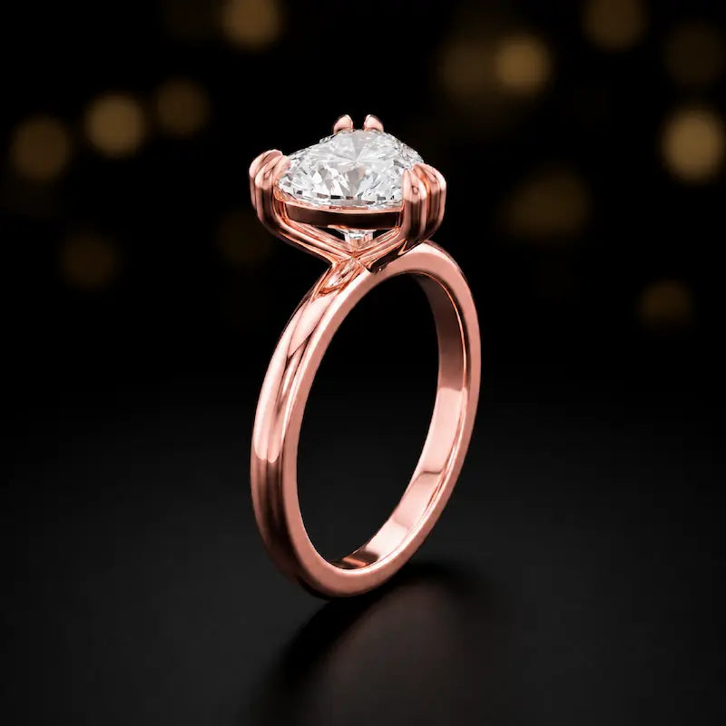 Front-on view of a 1.5 carat heart cut diamond solitaire engagement ring showing the full 18kt rose gold band and 6 claw cathedral setting by TJ Diamond