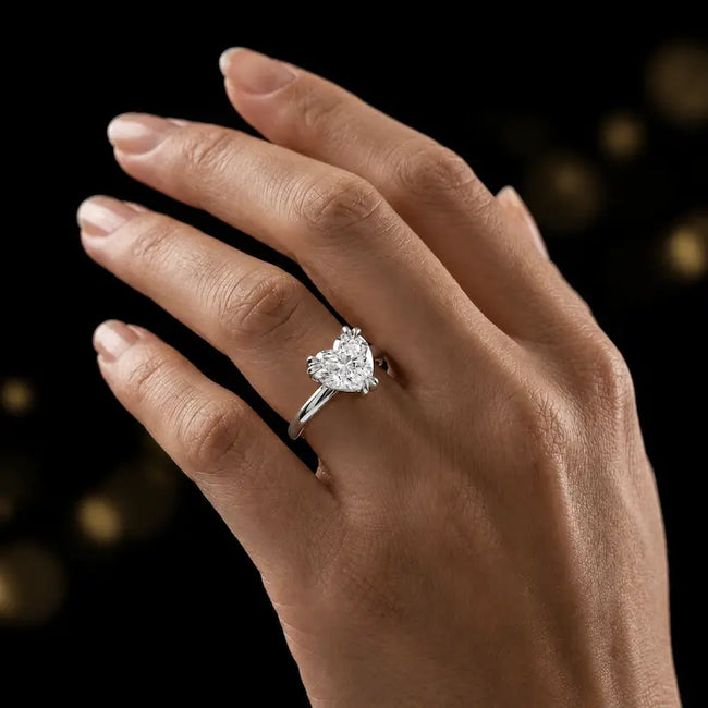 1.5 carat heart cut diamond solitaire engagement ring in an 18kt white gold 6 claw setting worn on a hand, by TJ Diamond