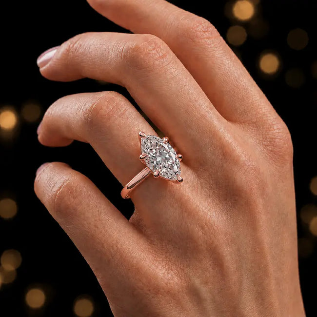 1.5 carat marquise cut diamond solitaire engagement ring in an 18kt rose gold 6 claw setting worn on a hand, by TJ Diamond