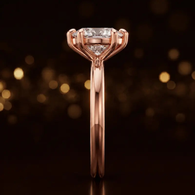 Side profile of a 1.5 carat oval cut diamond solitaire engagement ring showing the cathedral setting and 18kt rose gold band by TJ Diamond
