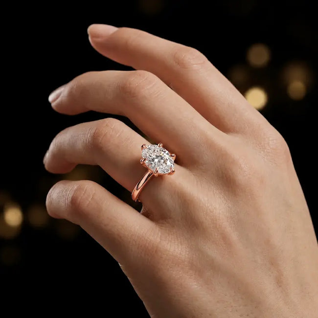 1.5 carat oval cut diamond solitaire engagement ring in an 18kt rose gold 6 claw setting worn on a hand, by TJ Diamond