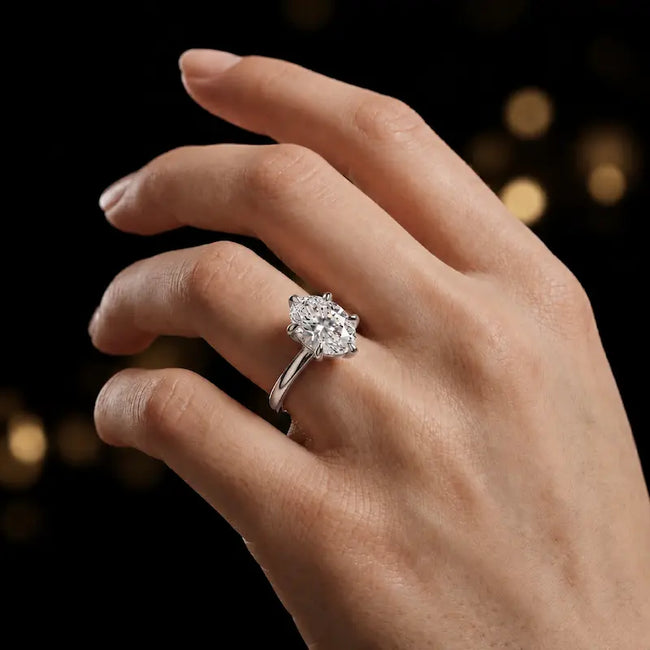 1.5 carat oval cut diamond solitaire engagement ring in an 18kt white gold 6 claw setting worn on a hand, by TJ Diamond