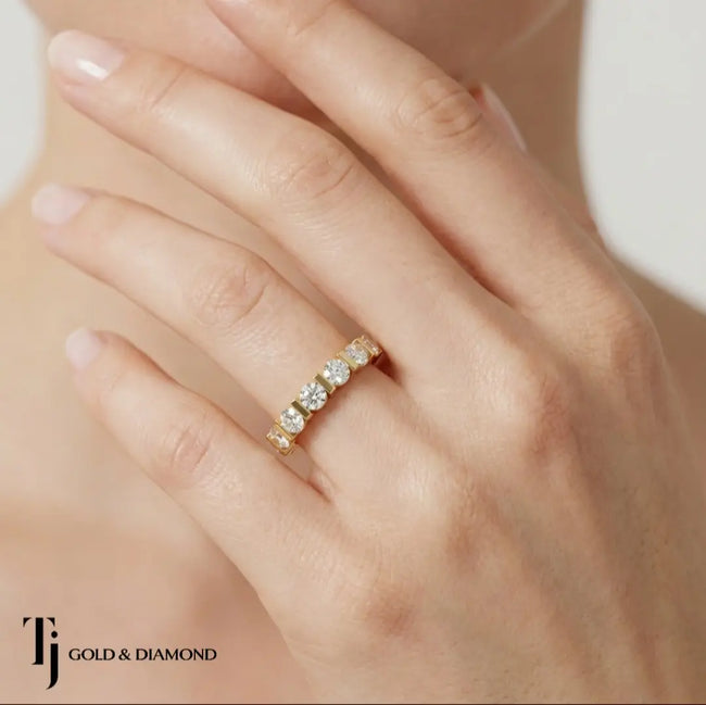 Close-up of Bar Half Eternity diamond wedding band on model's hand, 18kt yellow gold band with bar-set round diamonds