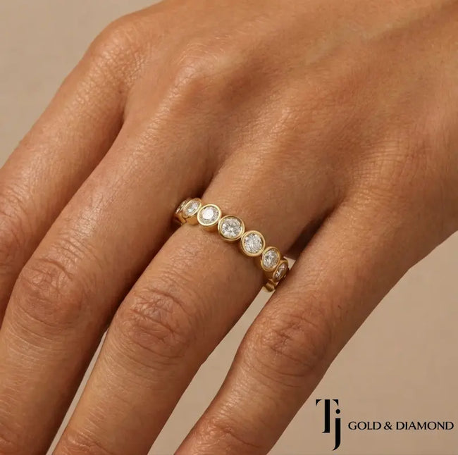 Bezel setting full eternity diamond wedding band in 18kt yellow gold worn on hand with round brilliant lab-grown diamonds.