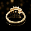 Back view of a cushion-cut three-stone lab-grown diamond ring in 18ct yellow gold, showing the open basket settings.