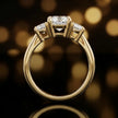 Side profile of a cushion-cut three-stone lab-grown diamond engagement ring in 18ct yellow gold, highlighting the elevated basket setting.