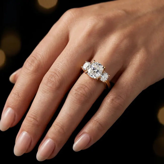 Model wearing a cushion-cut lab-grown diamond trilogy engagement ring in handcrafted 18ct yellow gold.
