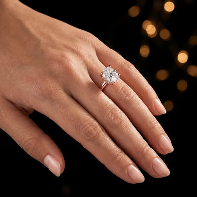 4-claw cushion cut engagement ring with hidden halo in 18kt rose gold, worn on hand