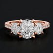 Front view of a cushion cut three-stone diamond engagement ring in 18kt rose gold, with a cushion cut centre stone, two cushion cut side stones, and diamond shoulders