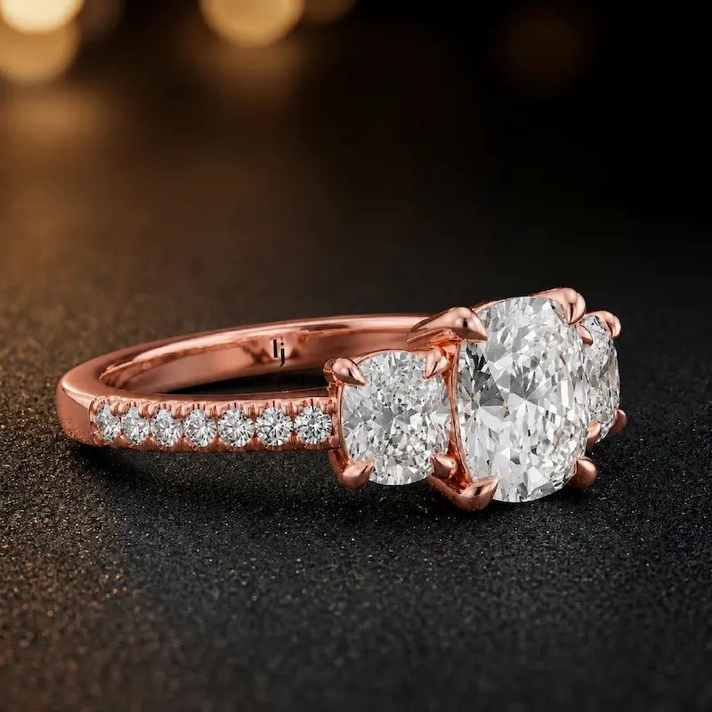 Side angle of a cushion cut three-stone diamond engagement ring in 18kt rose gold showing the trilogy setting and diamond shoulders
