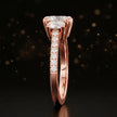 Side profile of a cushion cut three-stone diamond engagement ring in 18kt rose gold showing the band elevation and diamond shoulders