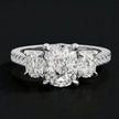 Front view of a cushion cut three-stone diamond engagement ring in 18kt white gold, with a cushion cut centre stone, two cushion cut side stones, and diamond shoulders