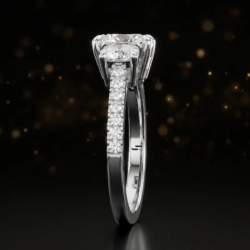 Side profile of a cushion cut three-stone diamond engagement ring in 18kt white gold showing the band elevation and diamond shoulders