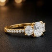Side view of a cushion cut three-stone lab-grown diamond engagement ring in 18kt yellow gold with diamond shoulders