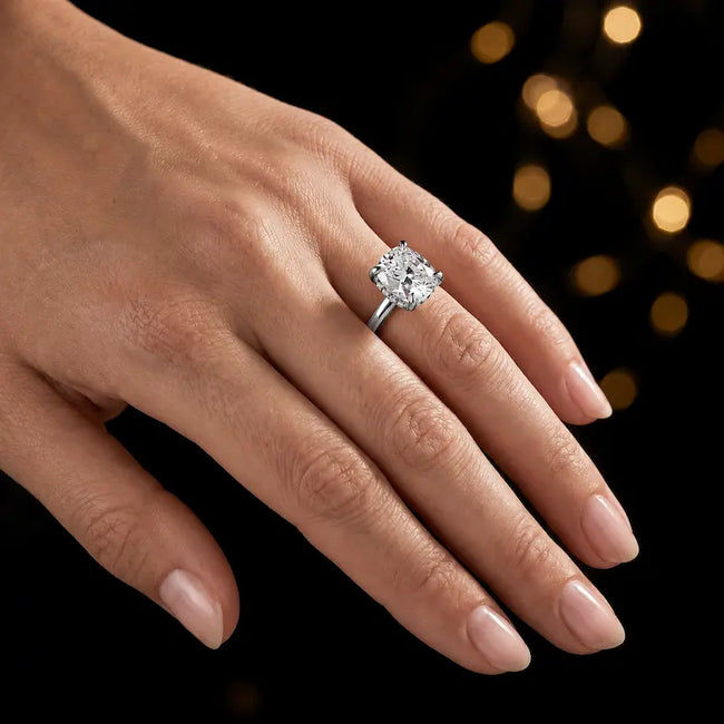 4-claw cushion cut engagement ring with hidden halo in 18kt white gold, worn on hand.