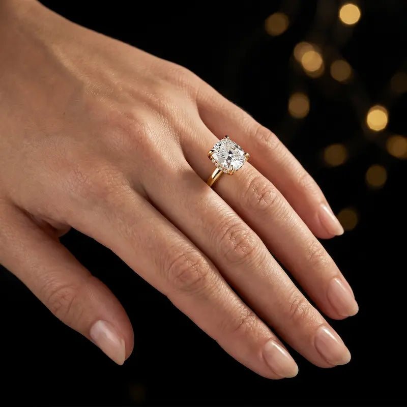 4-claw cushion cut engagement ring with hidden halo in 18kt yellow gold, worn on hand