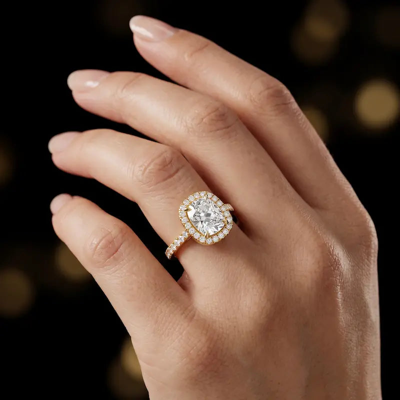 Cushion cut halo lab-grown diamond engagement ring worn on hand in 18kt yellow gold.