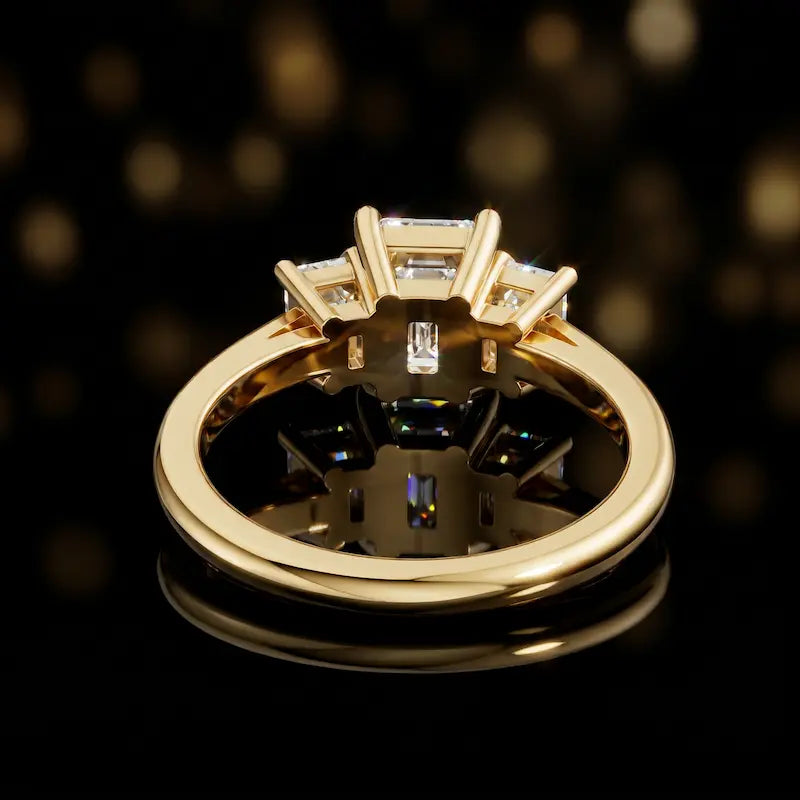 Rear view of an emerald-cut three-stone lab-grown diamond engagement ring in 18kt yellow gold, showcasing the open basket setting.