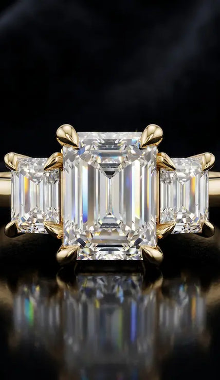 Front view of an emerald-cut lab-grown diamond trilogy engagement ring in 18kt yellow gold with matching emerald-cut side diamonds.