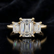 Front view of an emerald-cut lab-grown diamond trilogy engagement ring in 18kt yellow gold with matching emerald-cut side diamonds.
