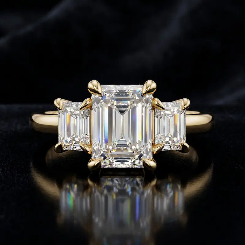 Front view of an emerald-cut lab-grown diamond trilogy engagement ring in 18kt yellow gold with matching emerald-cut side diamonds.