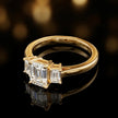 Side view of an emerald-cut three-stone lab-grown diamond engagement ring in 18kt yellow gold, highlighting the elevated basket setting.