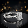 Angled view of 4-claw emerald cut engagement ring with hidden halo in 18kt white gold