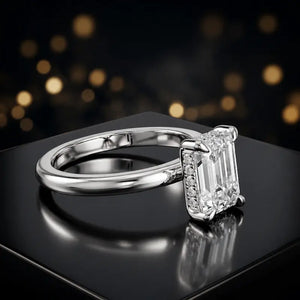 Angled view of 4-claw emerald cut engagement ring with hidden halo in 18kt white gold