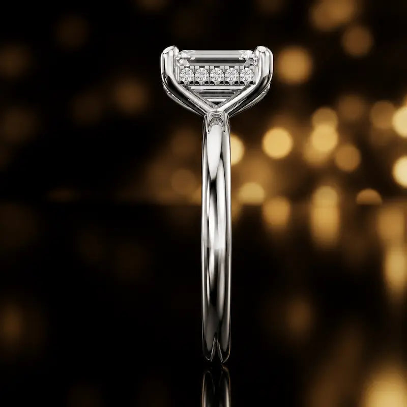 Side profile of 4-claw emerald cut engagement ring with hidden halo in 18kt white gold