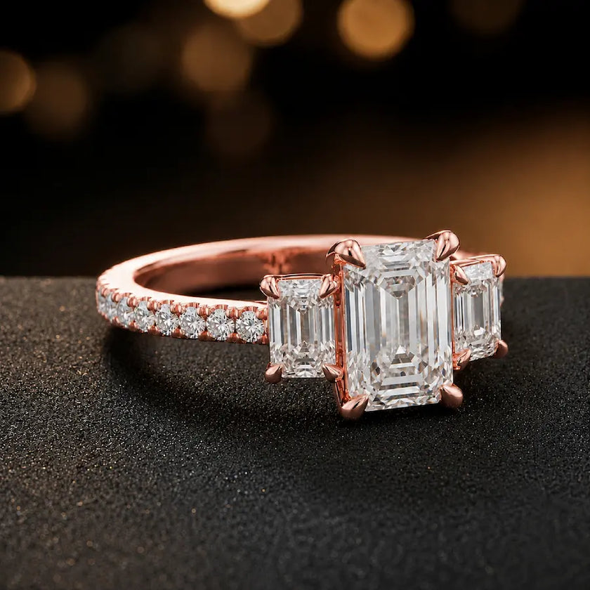 Side view of an emerald cut three-stone lab-grown diamond engagement ring in 18kt rose gold with diamond shoulders