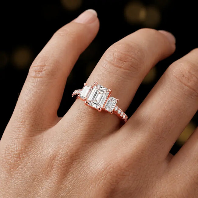 Emerald cut three-stone lab-grown diamond engagement ring in 18kt rose gold with diamond shoulders worn on hand