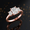 Angled view of an emerald-cut lab-grown diamond trilogy engagement ring in polished 18ct rose gold.