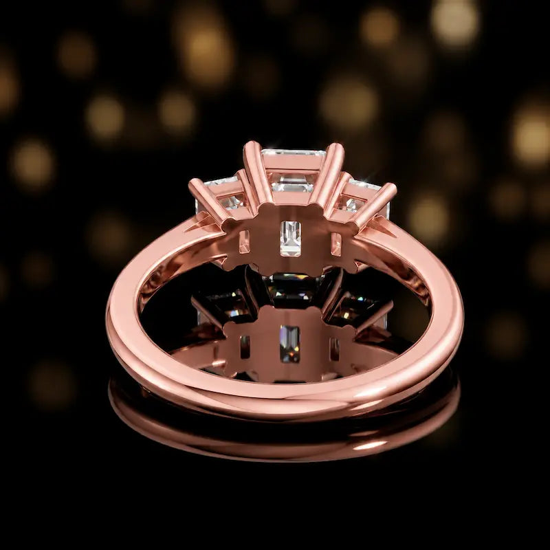 Rear view of an emerald-cut three-stone lab-grown diamond ring in 18ct rose gold, showing the open basket setting.