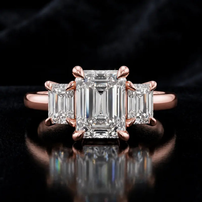 Front view of an emerald-cut lab-grown diamond trilogy engagement ring in 18ct rose gold with matching emerald-cut side diamonds.