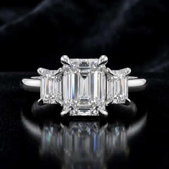Front view of an emerald-cut lab-grown diamond trilogy engagement ring in 18ct white gold with matching emerald-cut side diamonds.