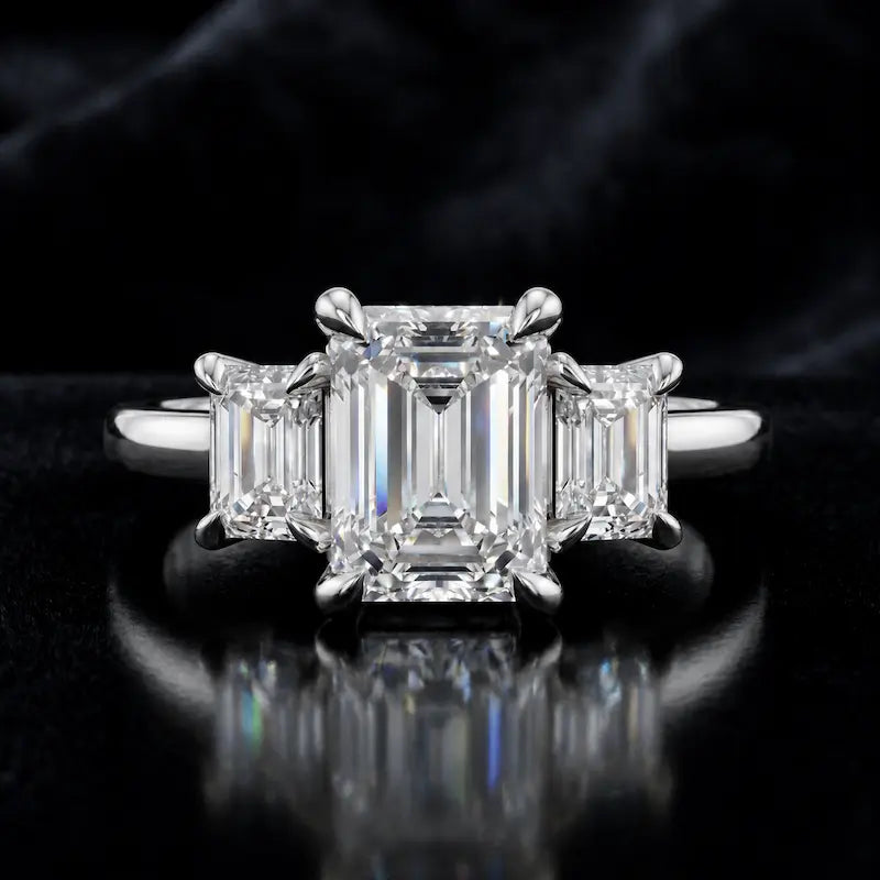 Front view of an emerald-cut lab-grown diamond trilogy engagement ring in 18ct white gold with matching emerald-cut side diamonds.