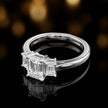Side view of an emerald-cut three-stone lab-grown diamond engagement ring in 18ct white gold, highlighting the elevated basket setting.