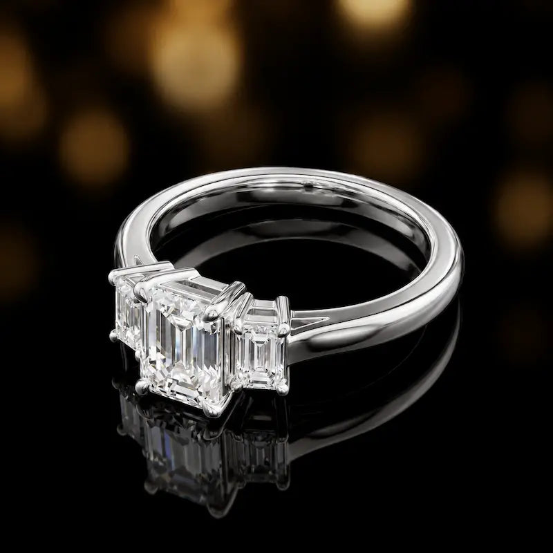 Side view of an emerald-cut three-stone lab-grown diamond engagement ring in 18ct white gold, highlighting the elevated basket setting.
